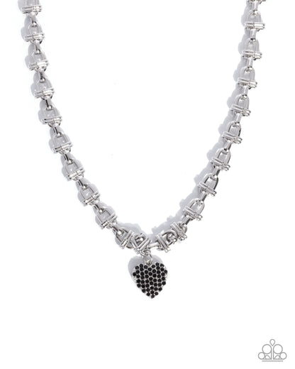 A silver-toned link chain necklace with a small heart-shaped pendant covered in black stones, shown on a plain white background.