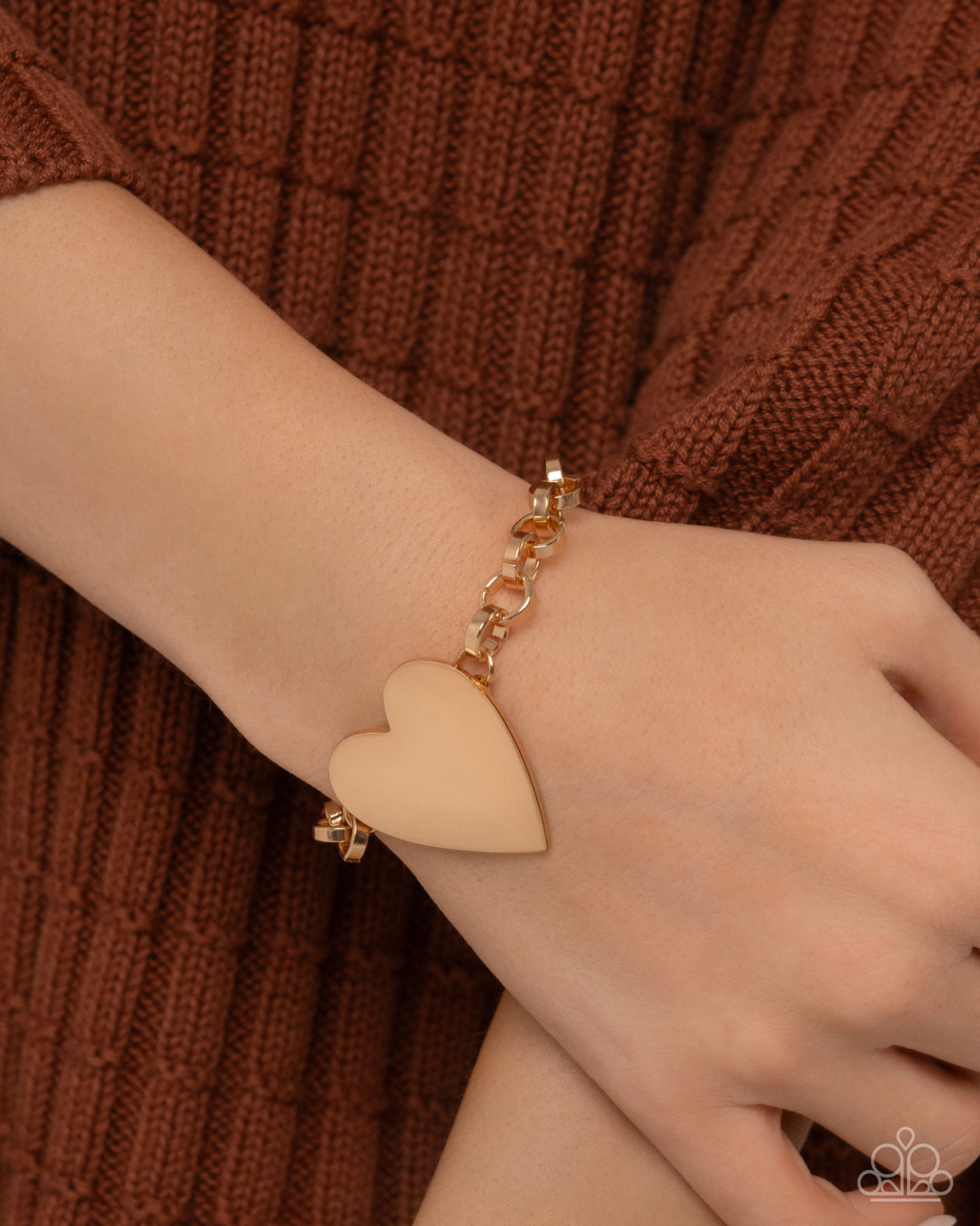 Heart-shaped bracelet on a wrist against a brown textured background