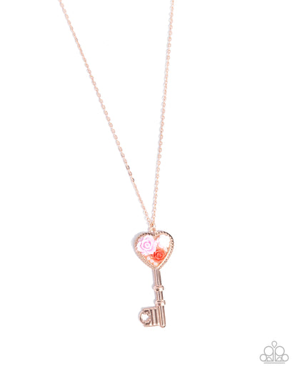 Rose gold key-shaped pendant necklace on a white background