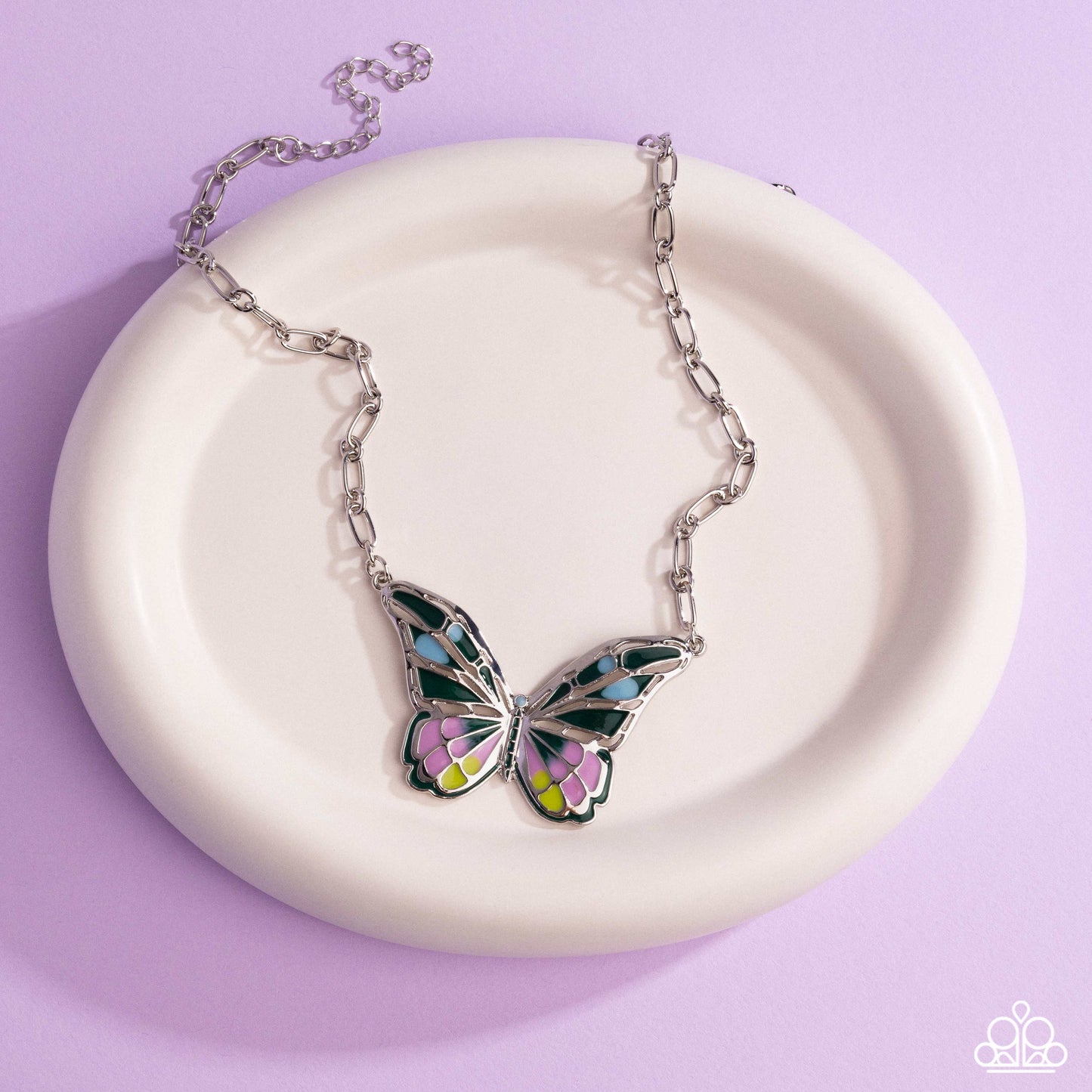 Butterfly necklace on a white dish with a purple background