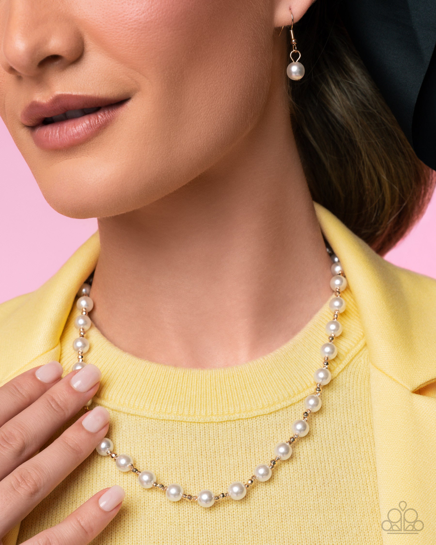 Close-up of a woman wearing a pearl necklace and earrings against a pink background