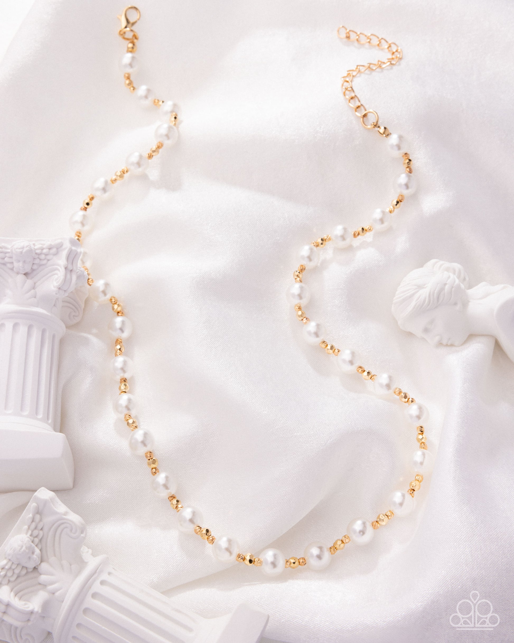 Pearl and gold necklace on a white classical sculpture background