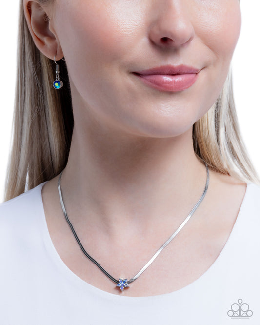 Close-up of a woman wearing a silver necklace with a purple pendant, against a white background.