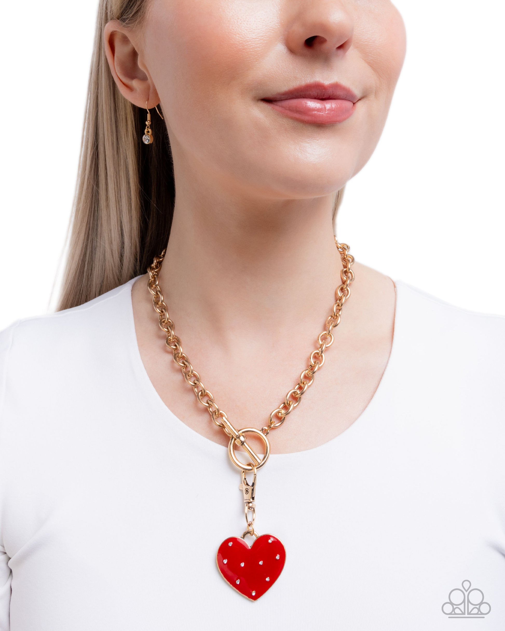 Woman wearing a gold chain necklace with a red heart pendant on a white background