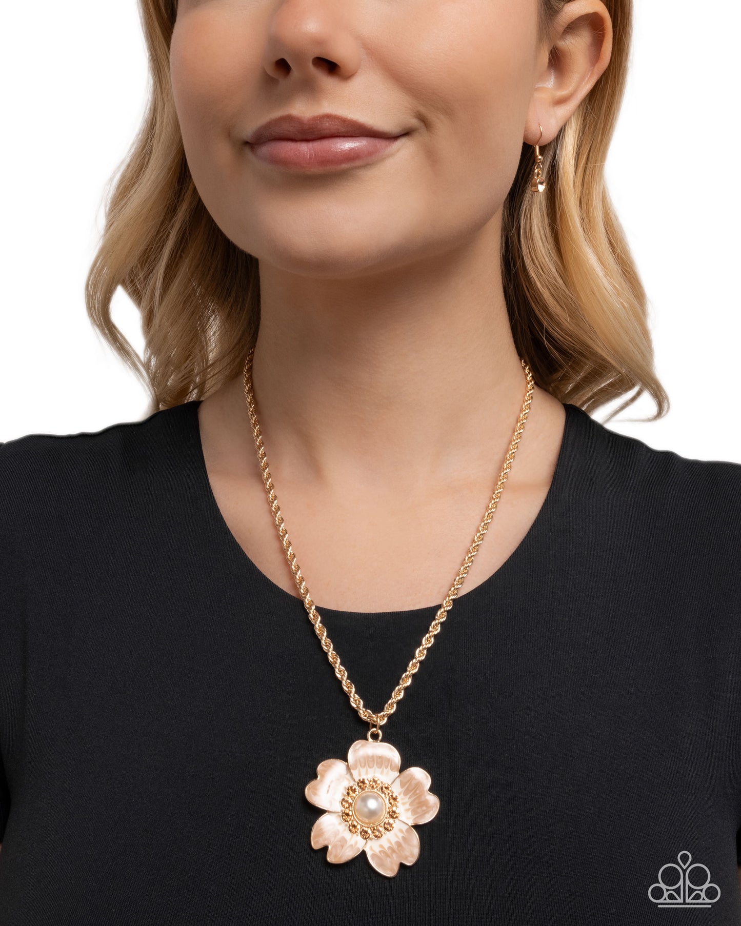 Woman wearing a gold flower pendant necklace on a plain background