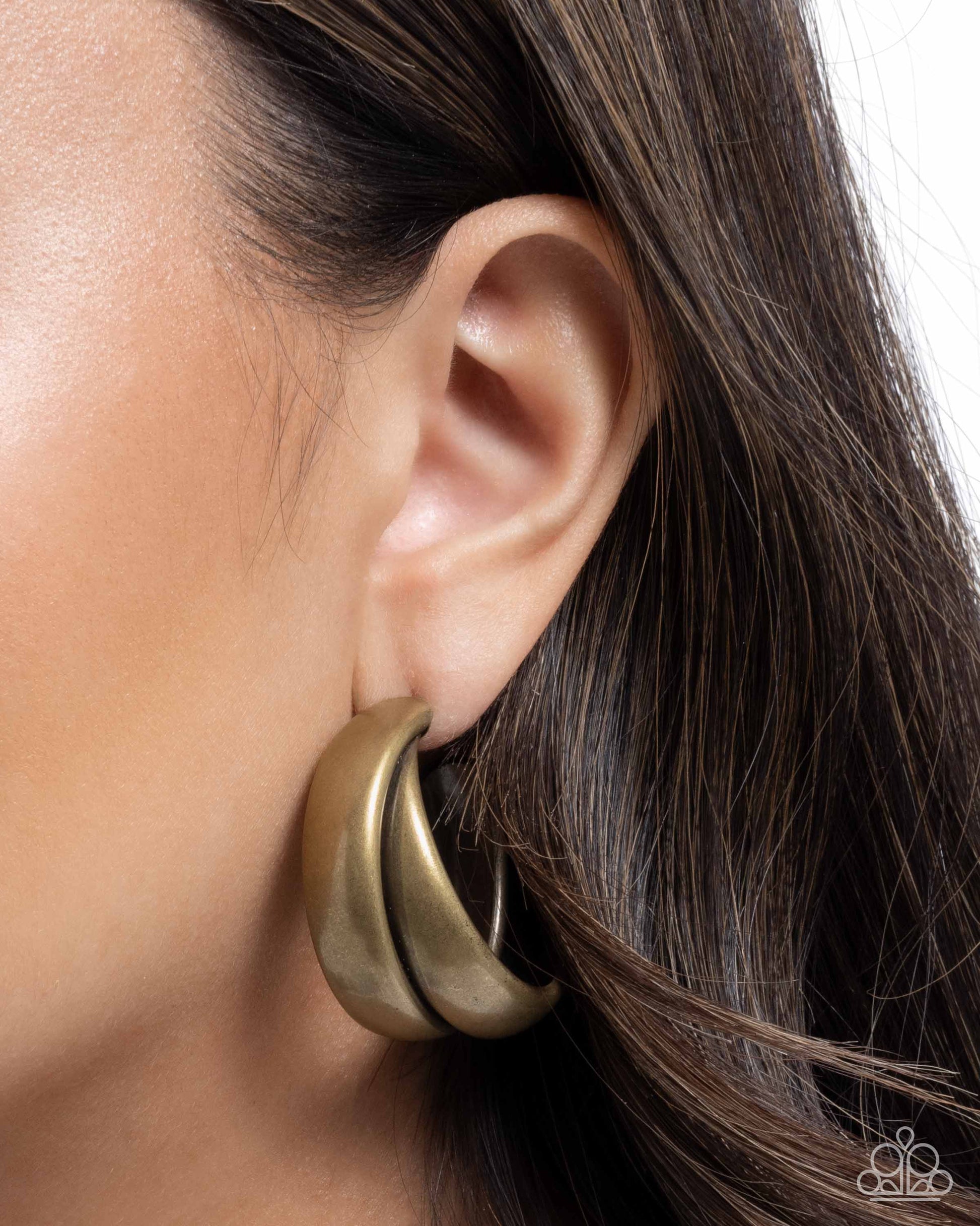 Close-up of a gold hoop earring worn by a person with dark hair.