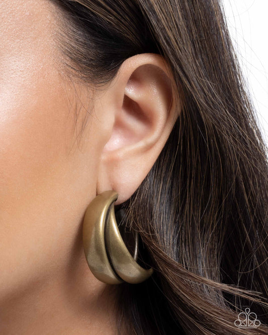 Close-up of a gold hoop earring worn by a person with dark hair.