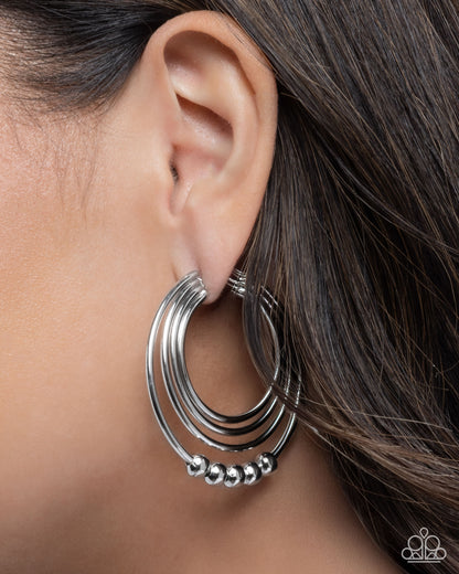 Silver hoop earring worn by a person with dark hair.