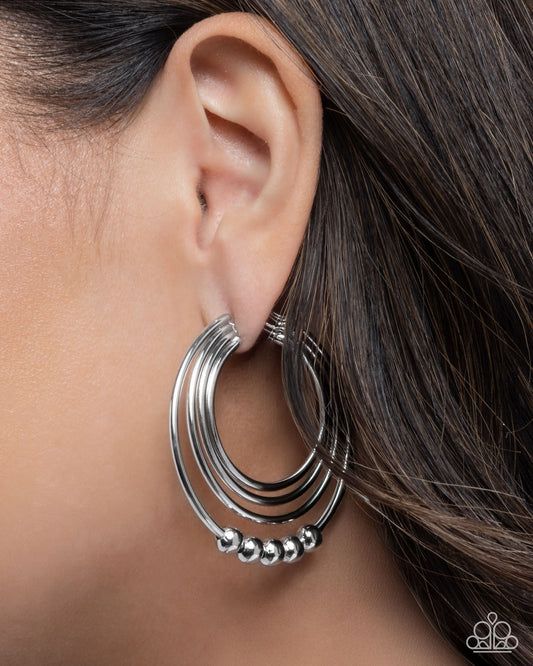 Silver hoop earring worn by a person with dark hair.