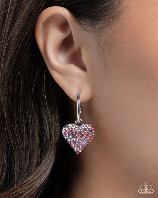 Heart-shaped earring worn on an ear with a blurred background