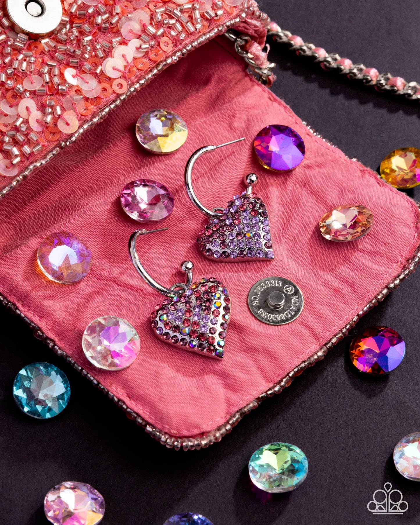 Heart-shaped earrings with rhinestones on a pink fabric surface