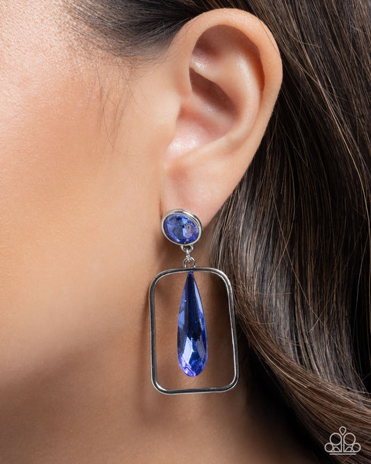 Blue teardrop earring worn on an ear with a blurred background