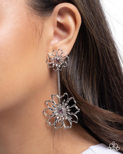 Silver floral earrings worn by a model with brown hair.