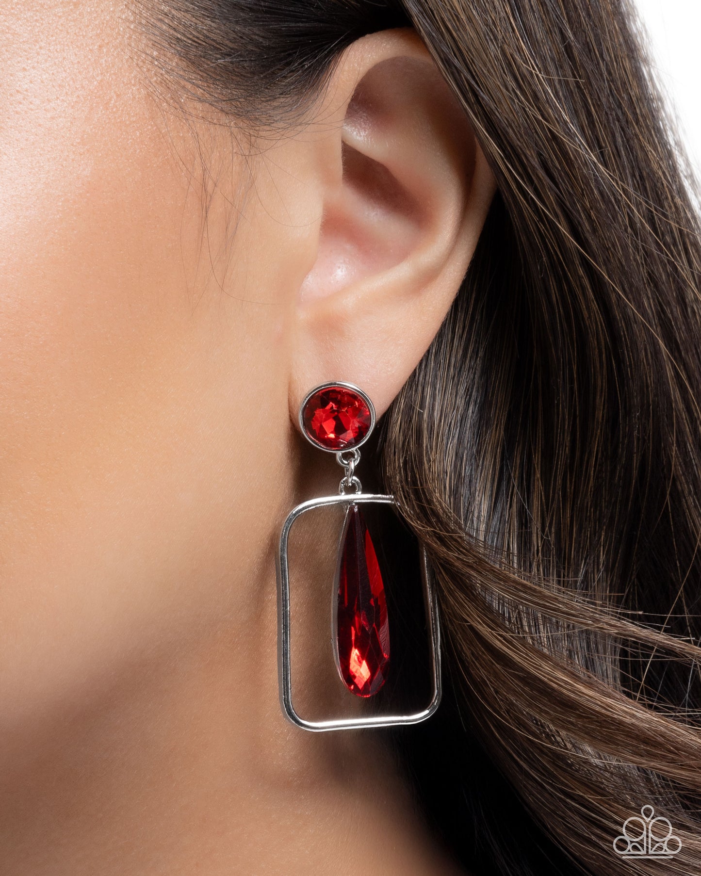 Red earring worn by a person with brown hair.