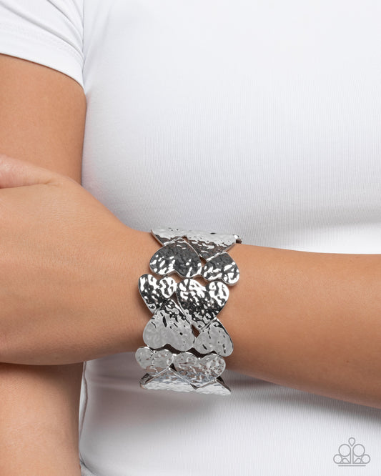 Silver bracelet on a wrist with a white background