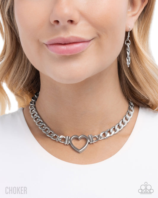 Silver chain choker with heart detail worn by a model on a white background