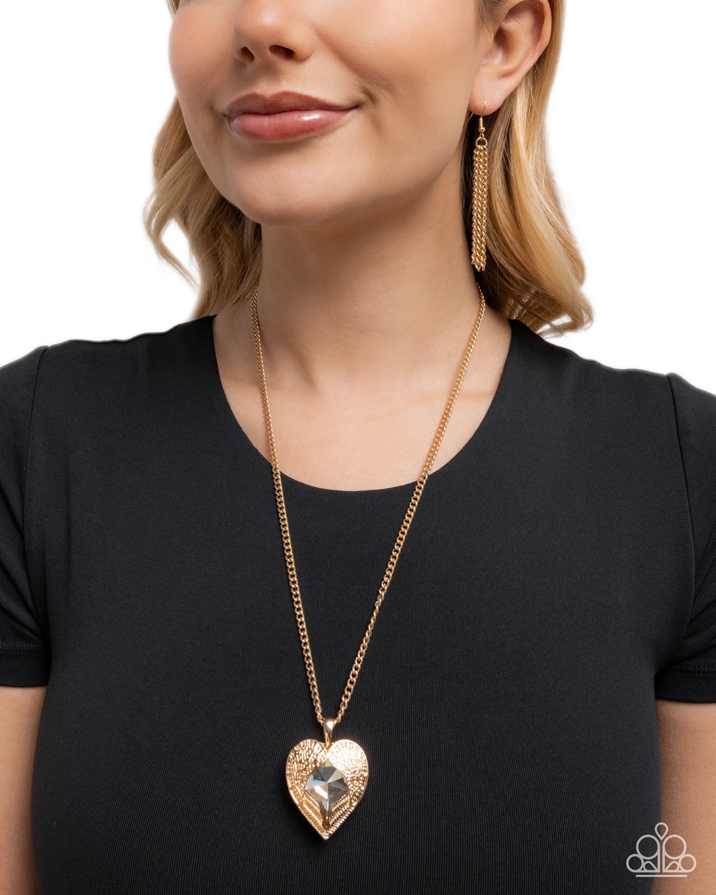 Woman wearing a gold heart-shaped necklace and earrings on a white background