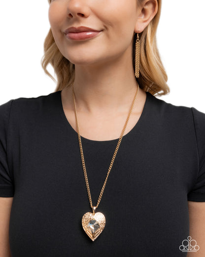 Woman wearing a gold heart-shaped necklace and earrings on a white background