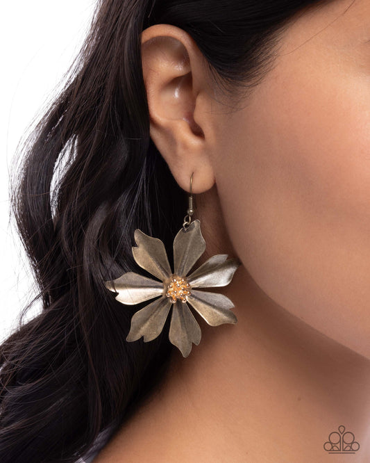 Floral earring worn by a person with dark hair on a neutral background