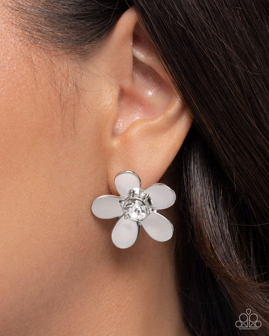 Flower-shaped earring worn on an ear with a blurred background