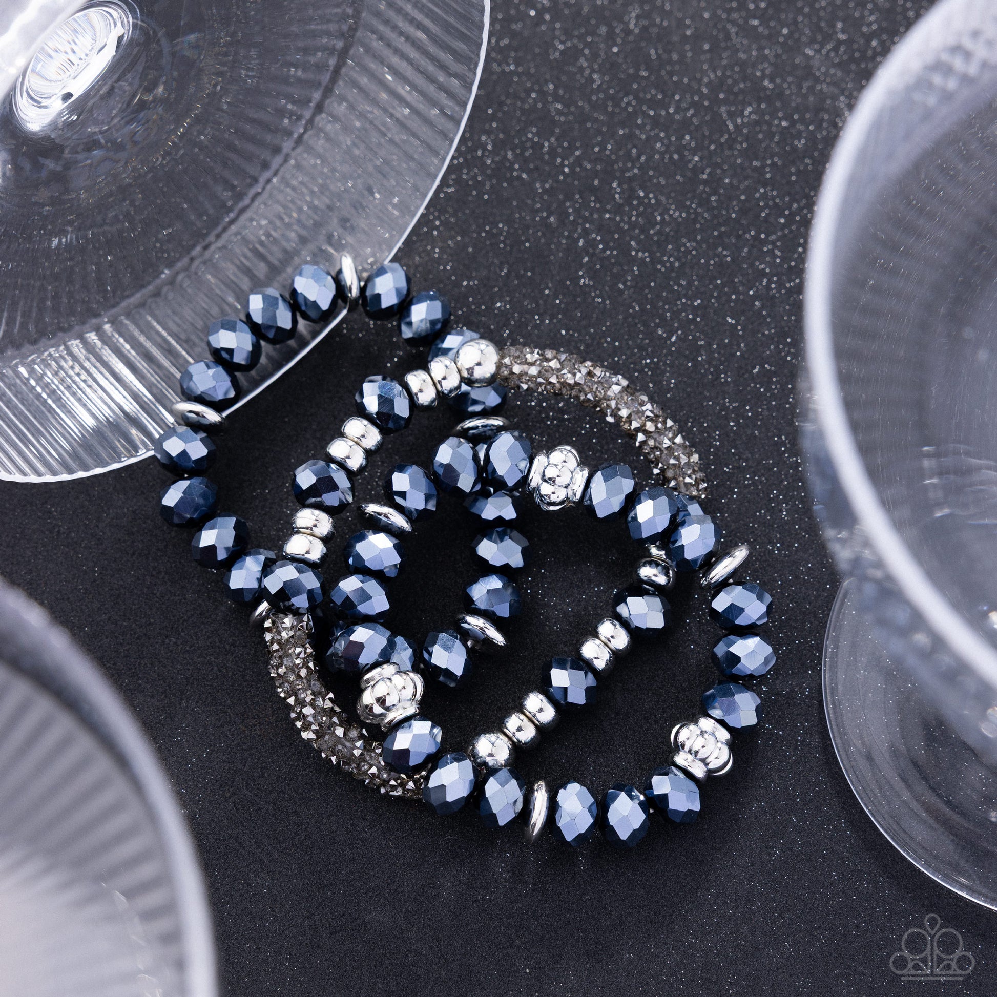 Blue beaded bracelet on a dark surface with clear plastic cups