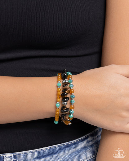 Person wearing a stack of beaded bracelets on a plain background