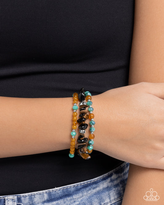 Person wearing a stack of beaded bracelets on a plain background