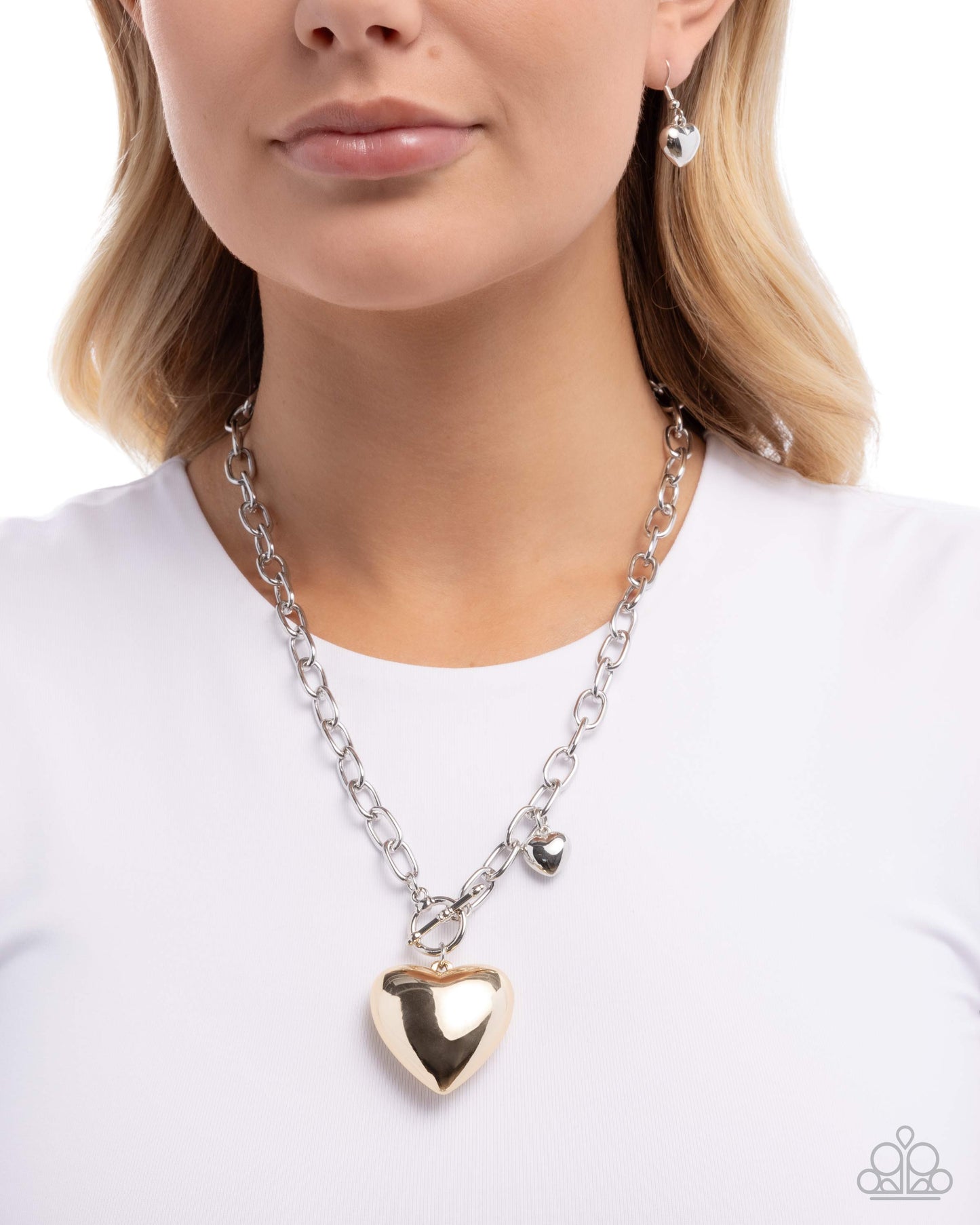 Woman wearing a silver chain necklace with a heart pendant on a white background
