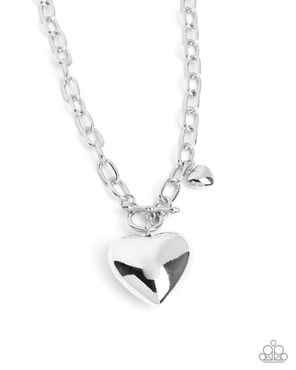 Silver heart-shaped pendant on a chain against a white background