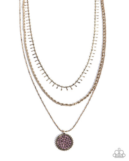 Layered gold necklaces with a purple pendant on a white background