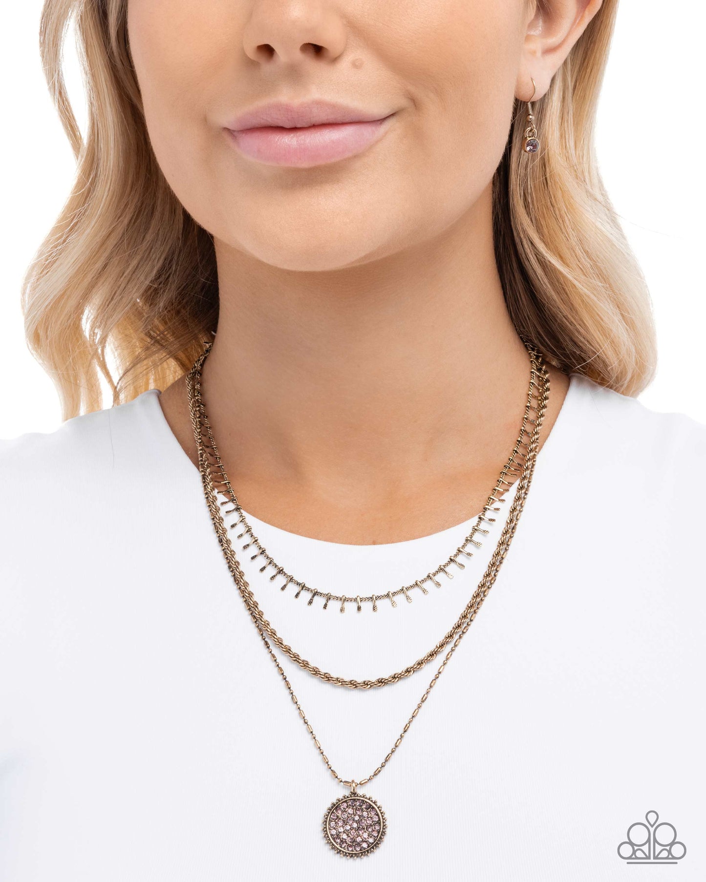 Woman wearing a gold necklace with a white top on a plain background