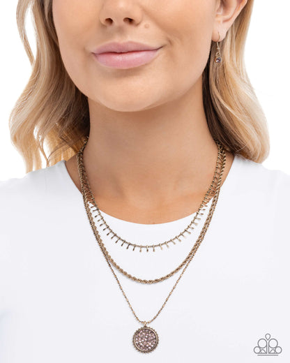 Woman wearing a gold necklace with a white top on a plain background
