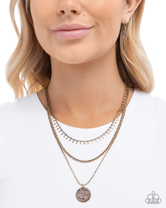Woman wearing a gold necklace with a white top on a plain background
