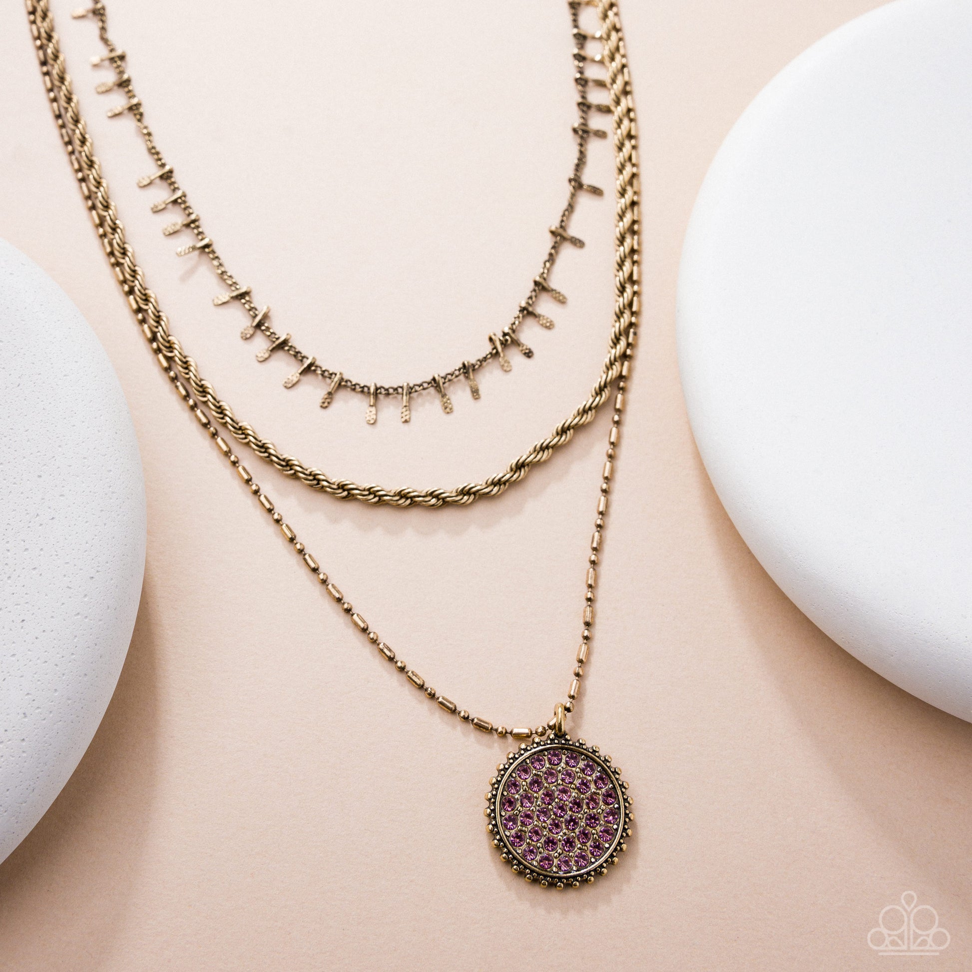 Two gold necklaces with intricate designs on a beige surface
