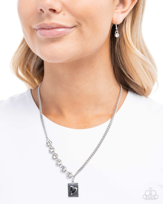Woman wearing a silver necklace with a heart pendant on a white background