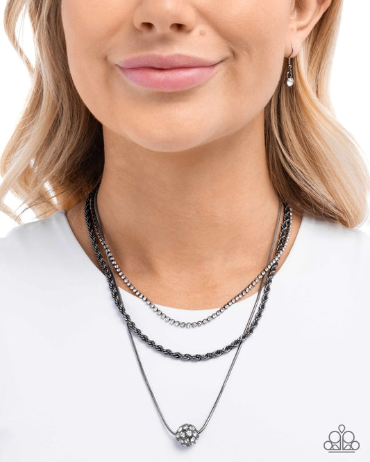 Woman wearing a stack of black and silver necklaces on a white background