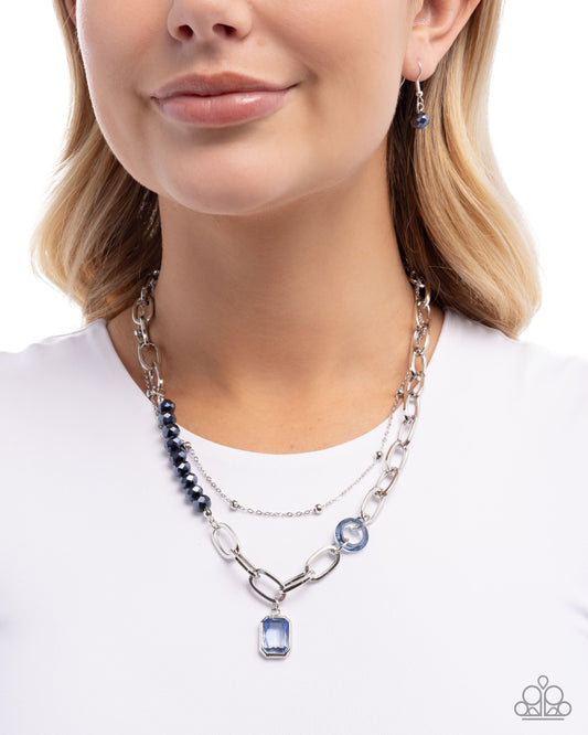 Woman wearing a silver chain necklace with blue gemstones on a white background
