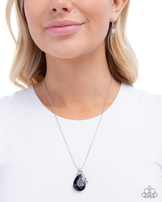 Woman wearing a silver necklace with a purple teardrop pendant on a white background
