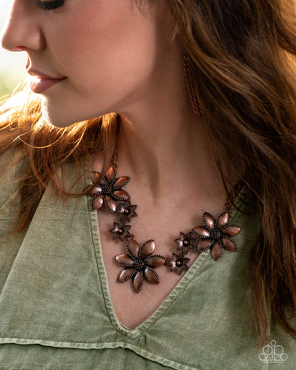 Close-up of a woman wearing a floral necklace with a green top.