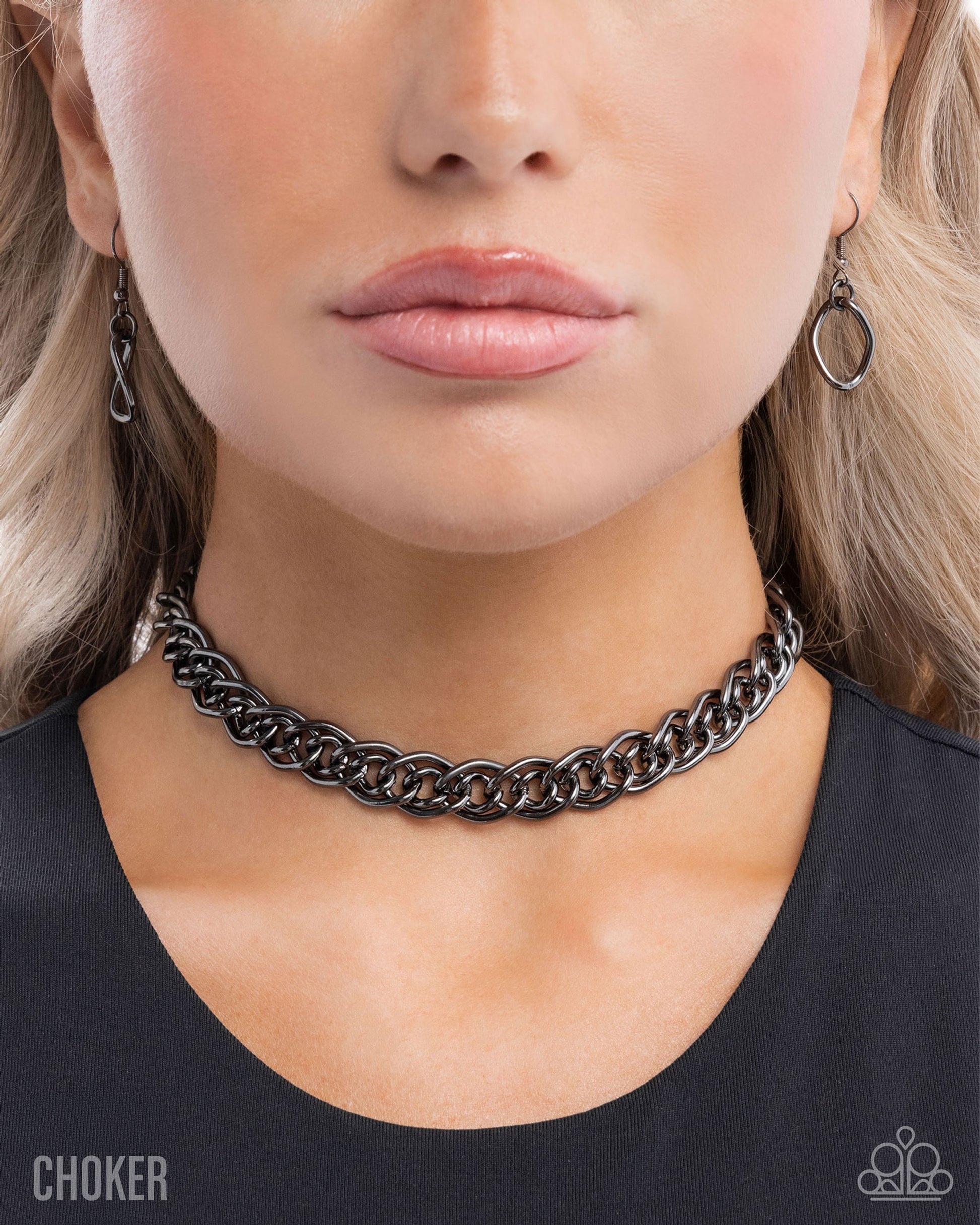 Close-up of a person wearing a black chain choker necklace and earrings.