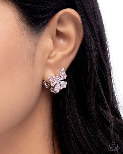 Butterfly-shaped earring worn on an ear with dark hair.