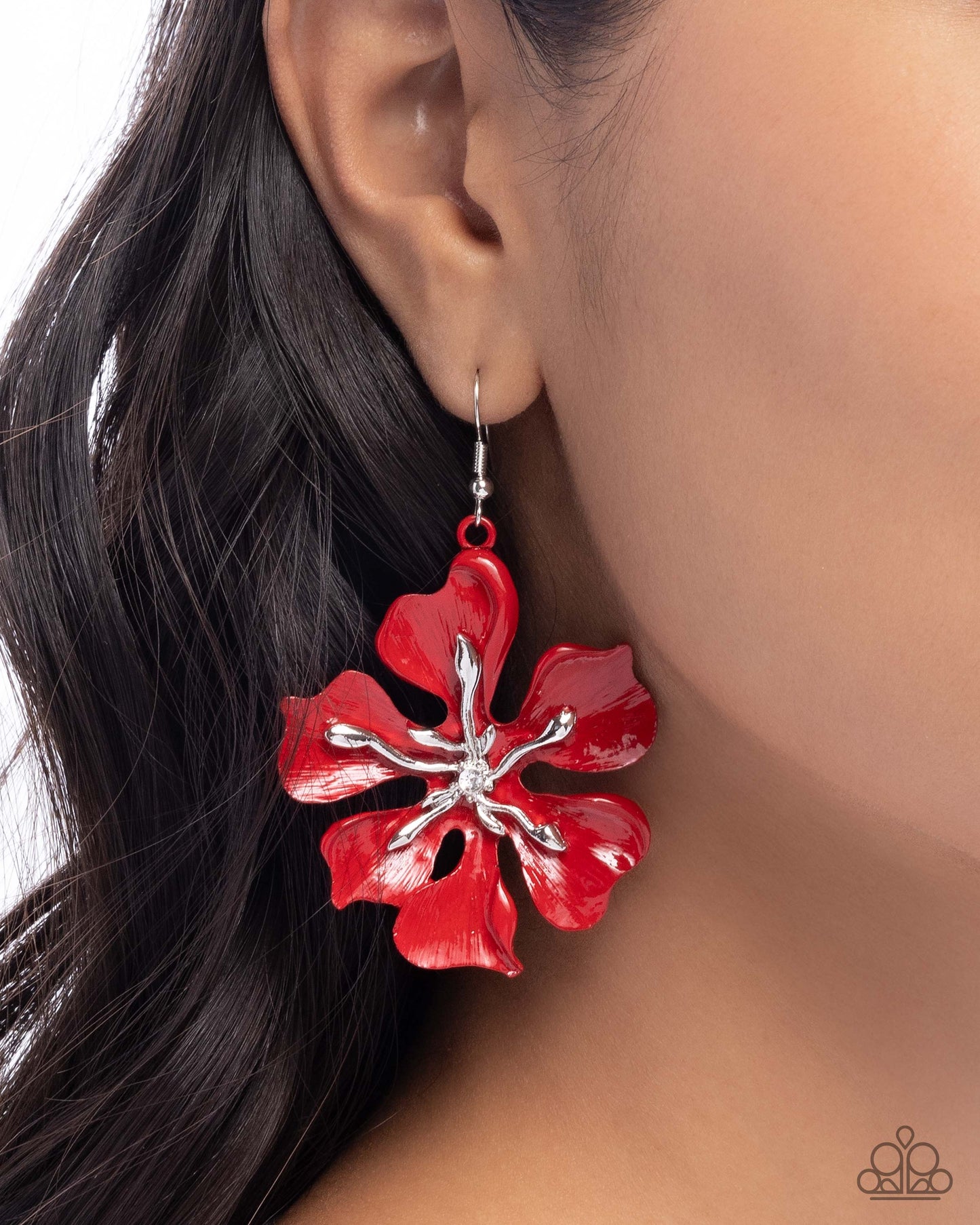 Red floral earring worn by a person with dark hair.