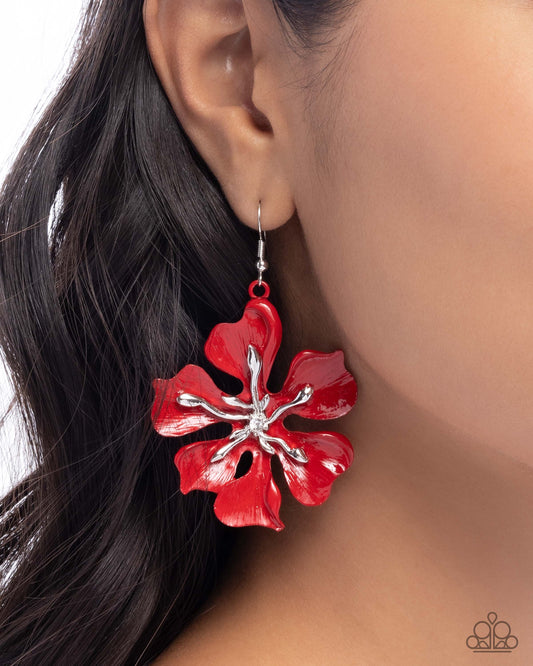 Red floral earring worn by a person with dark hair.