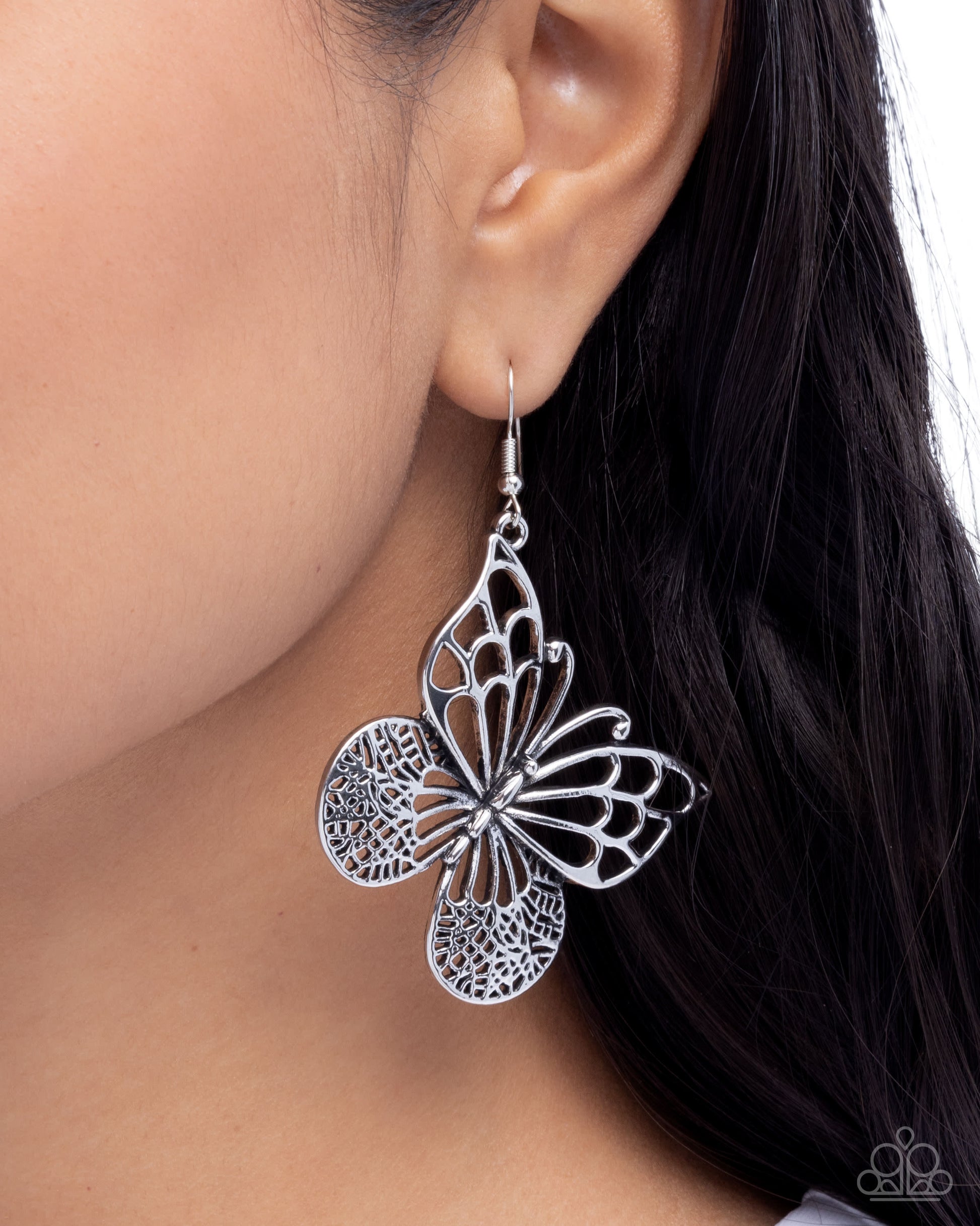 Silver butterfly earrings worn by a model with dark hair.