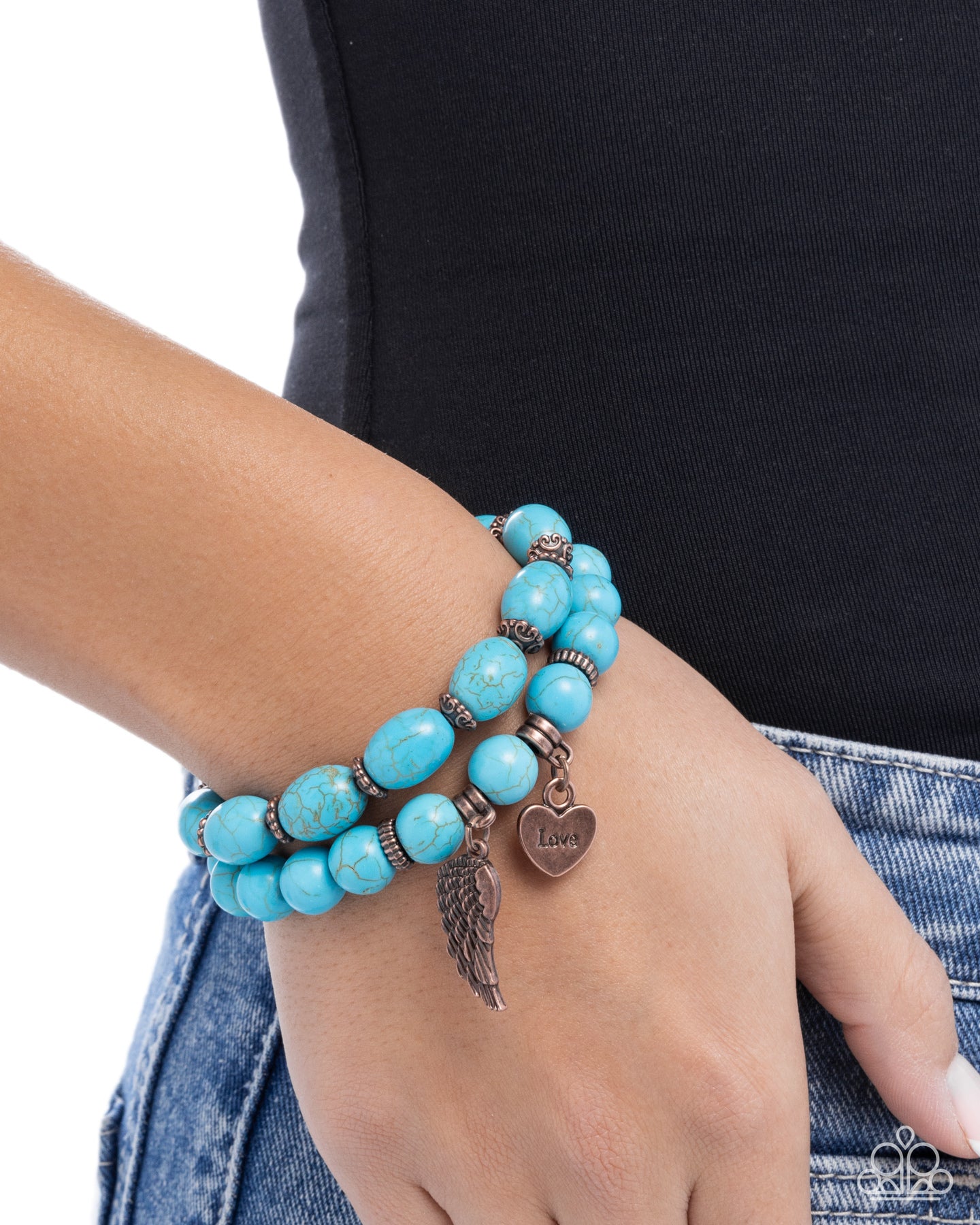 Turquoise beaded bracelet with heart and leaf charms on a wrist against a black background