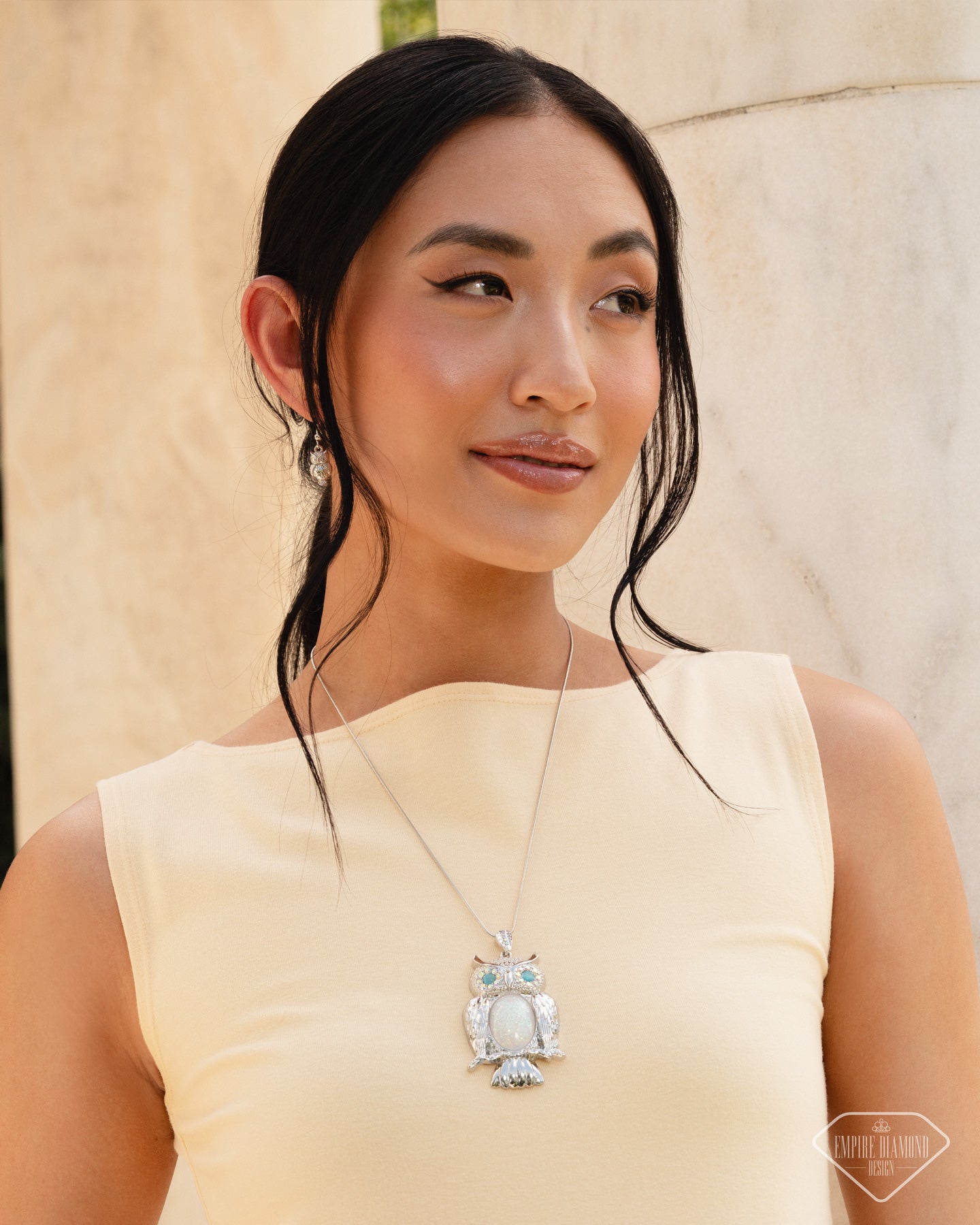 Woman wearing a yellow dress with a large decorative brooch against a neutral background