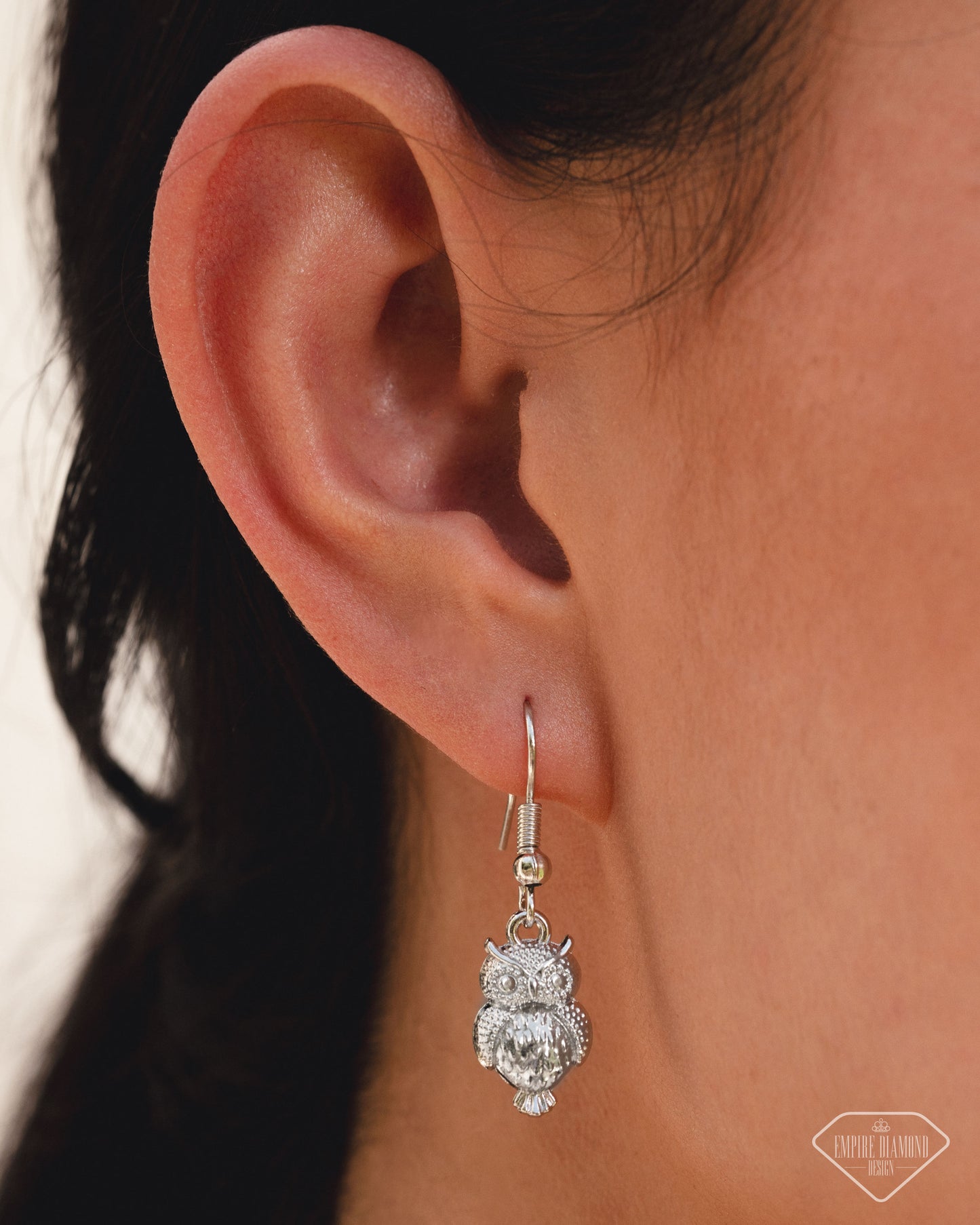 Close-up of an ear wearing a sparkling silver earring with a blurred background