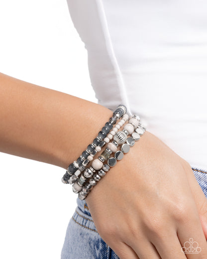 Stack of beaded bracelets on a wrist with a white background