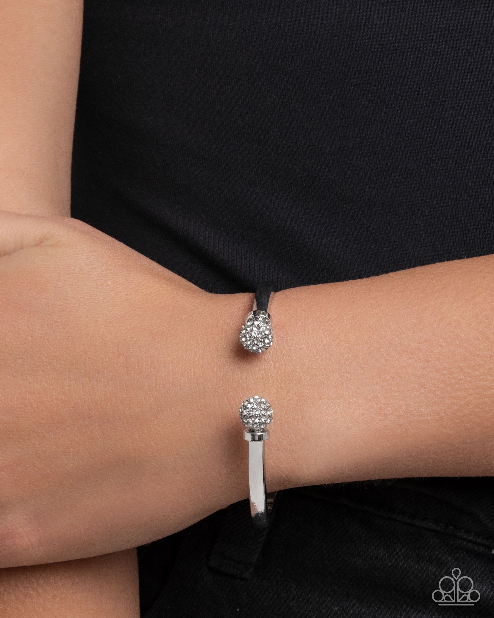 Silver bracelet with clear gemstones on a wrist against a black background