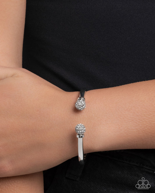 Silver bracelet with clear gemstones on a wrist against a black background